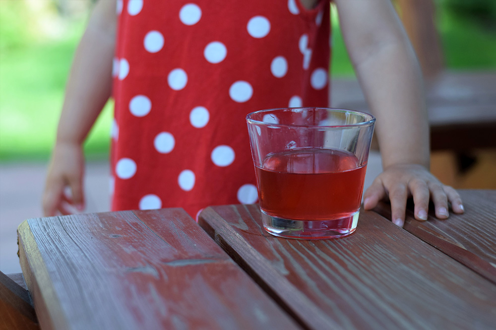 Ríbezľová limonáda na stole a pri nej dieťa