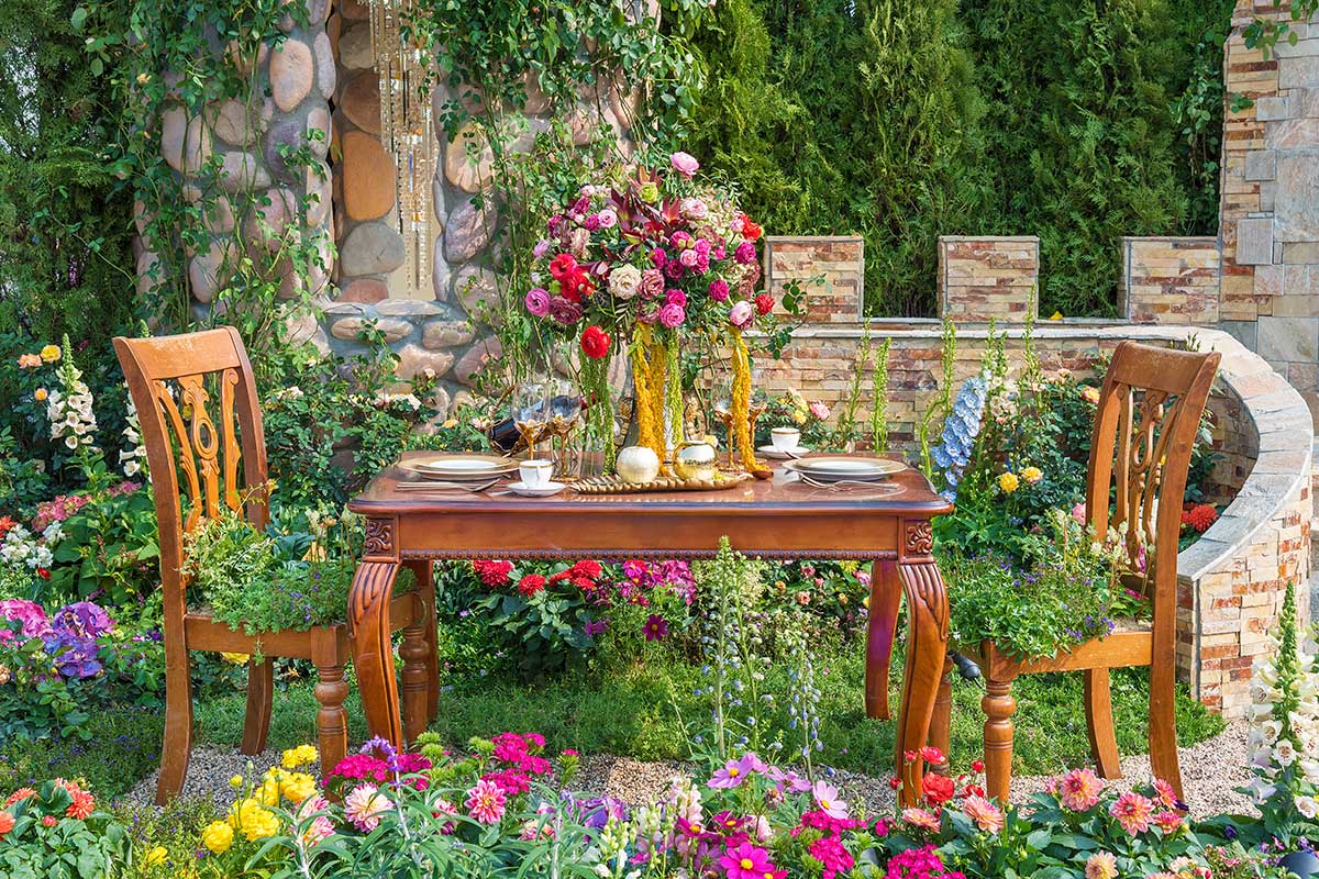 Kvetinová záhrada s dreveným stolom a stoličkami